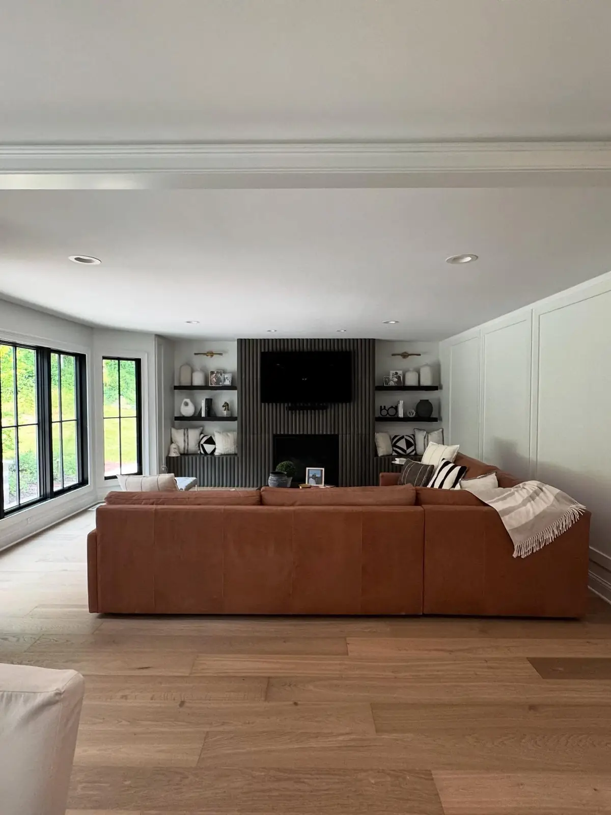 Renovated living space with a fireplace wall, built-in shelving and a leather sectional
