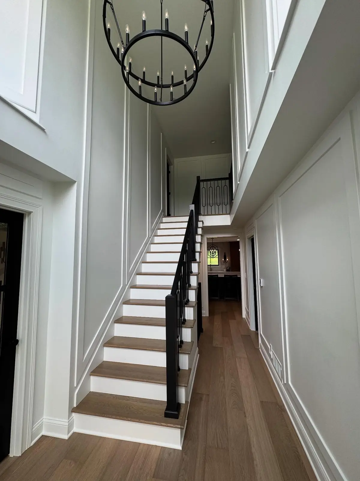 Staircase after — white treads, black railing and iron chandelier