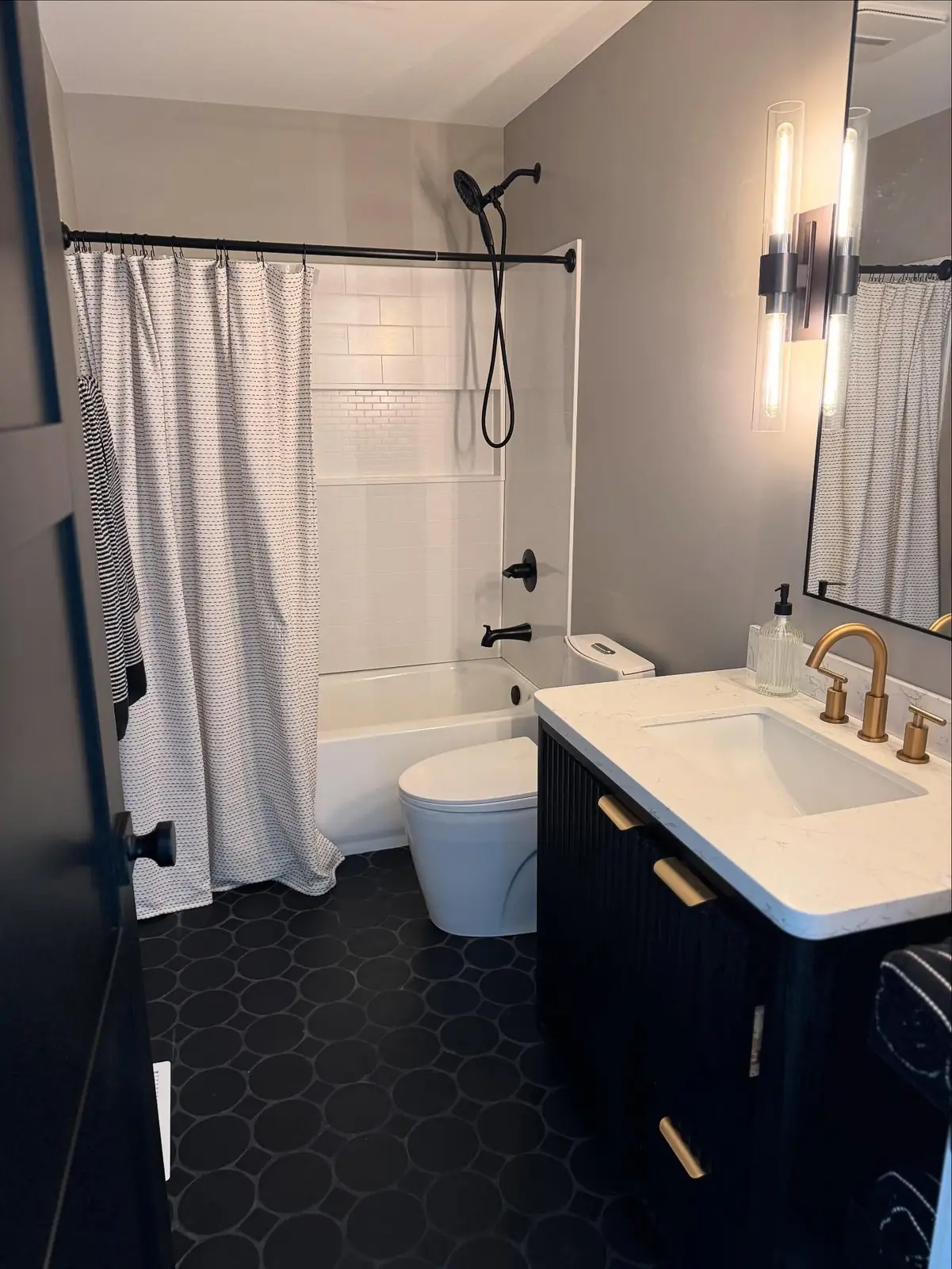 Bathroom after — navy vanity and black hex floor