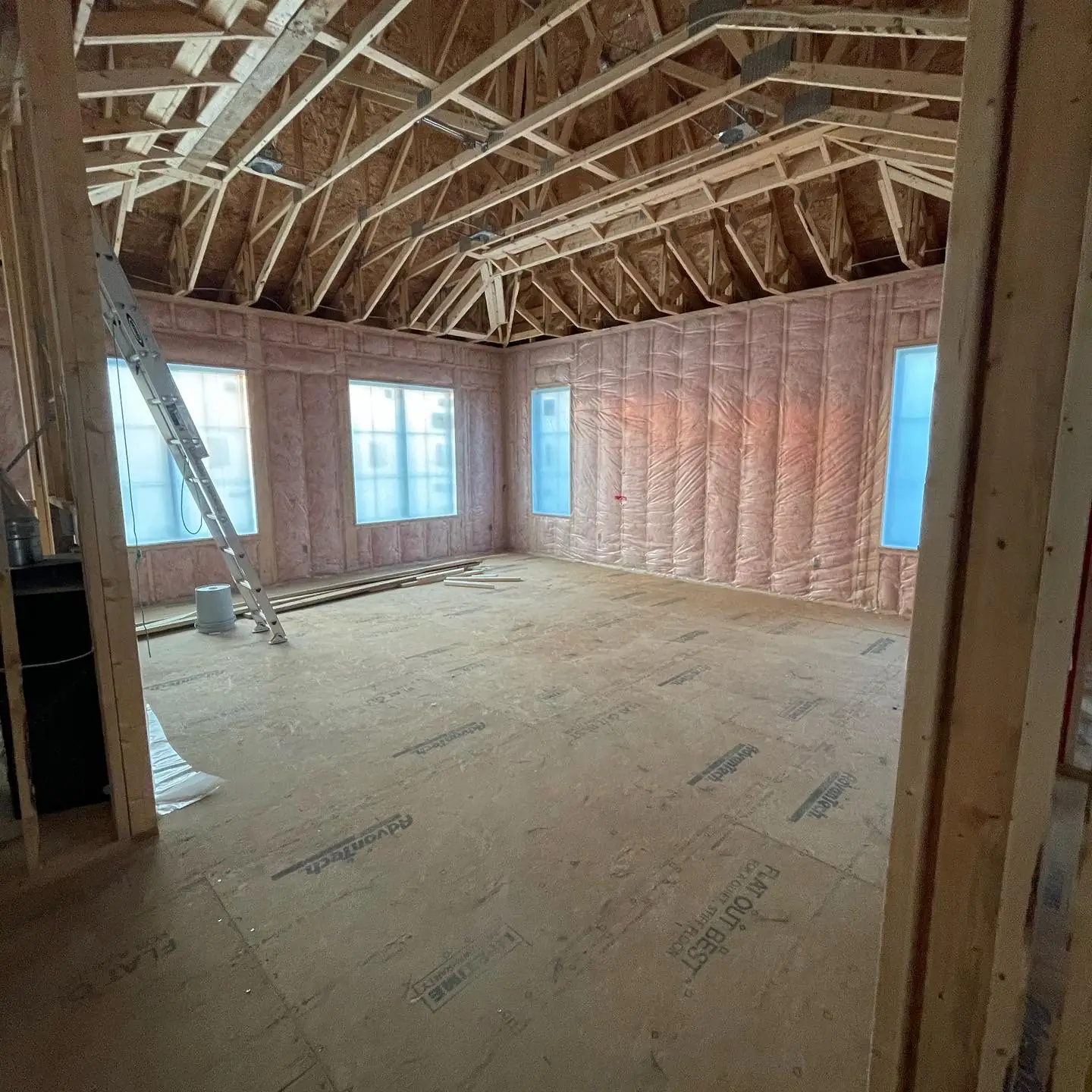 Primary bedroom at the framing stage — exposed trusses, insulation and subfloor