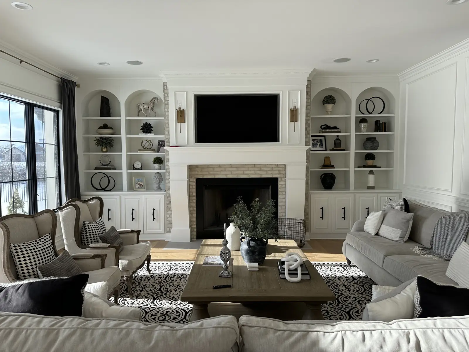 Fireplace framed by arched built-ins — French-Inspired Residence