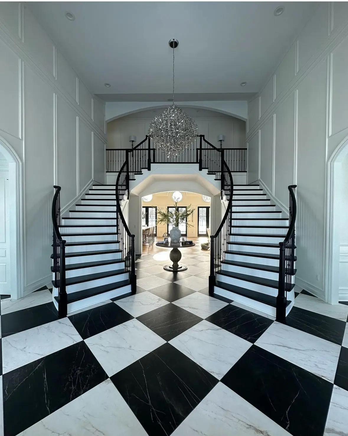 Twin curved staircases over checkerboard marble — French-Inspired Residence