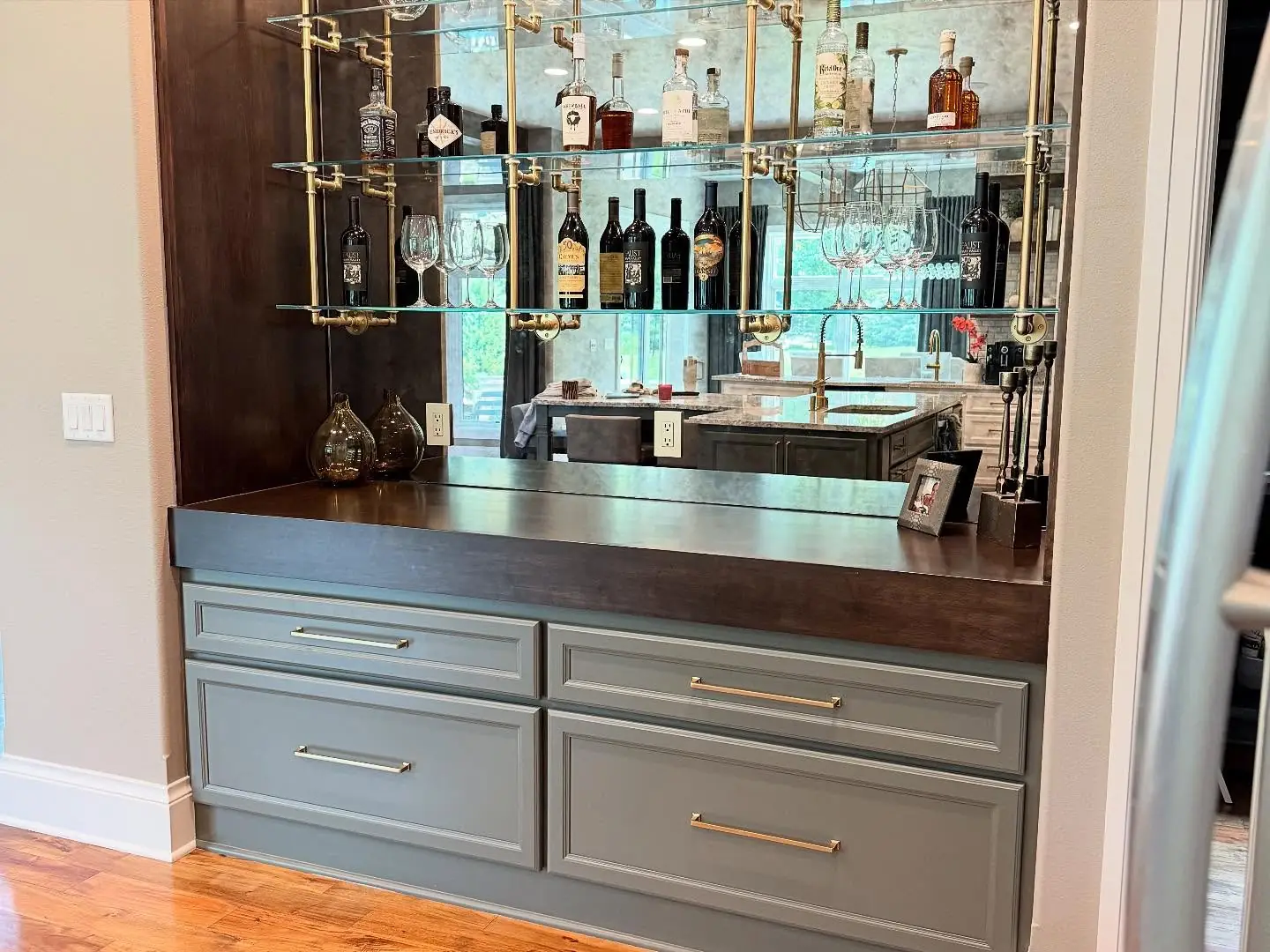 Bar after — glass shelving, a mirrored back and dark wood counter