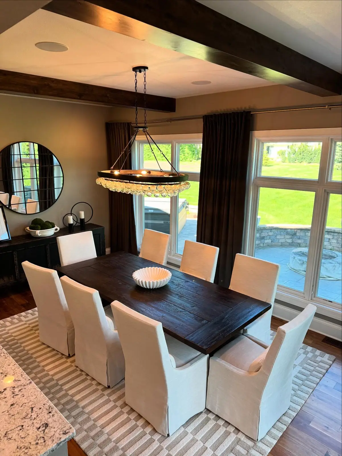 Dining room after — white slipcovered chairs beneath a beaded chandelier