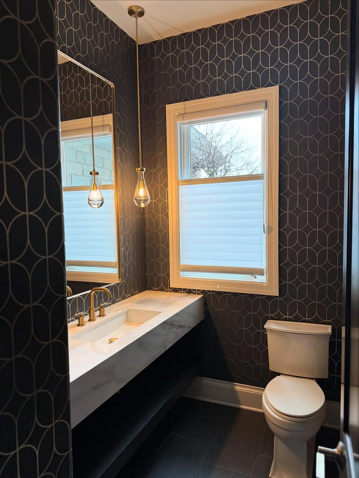Powder room after — black geometric wallpaper and a floating stone vanity