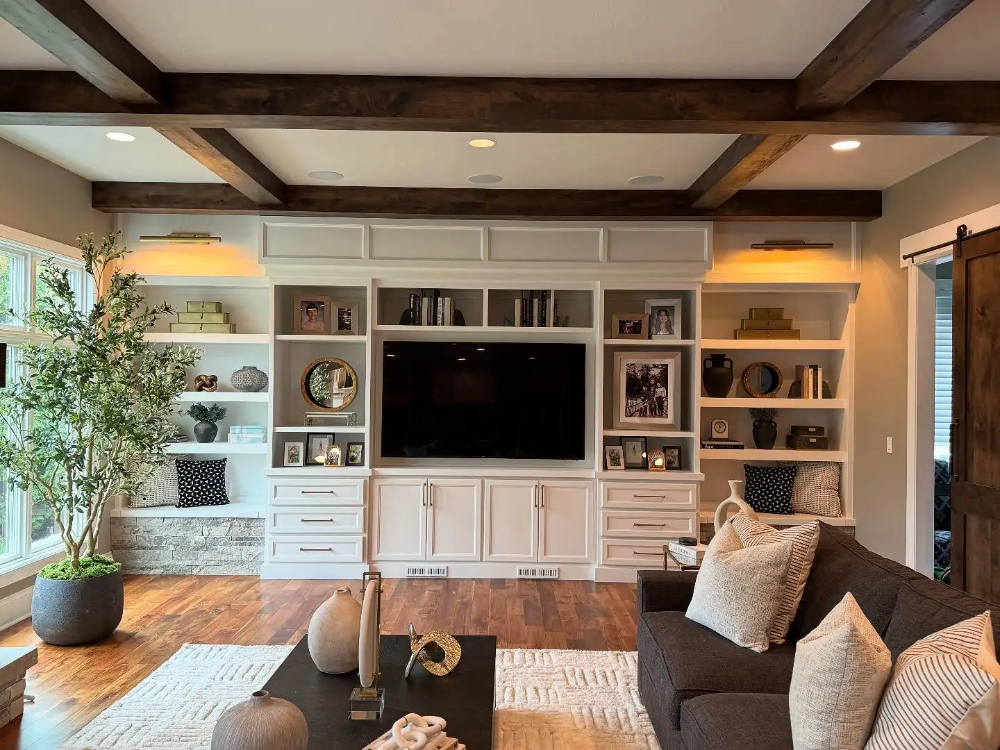 Legend View living room with white built-ins beneath dark wood beams