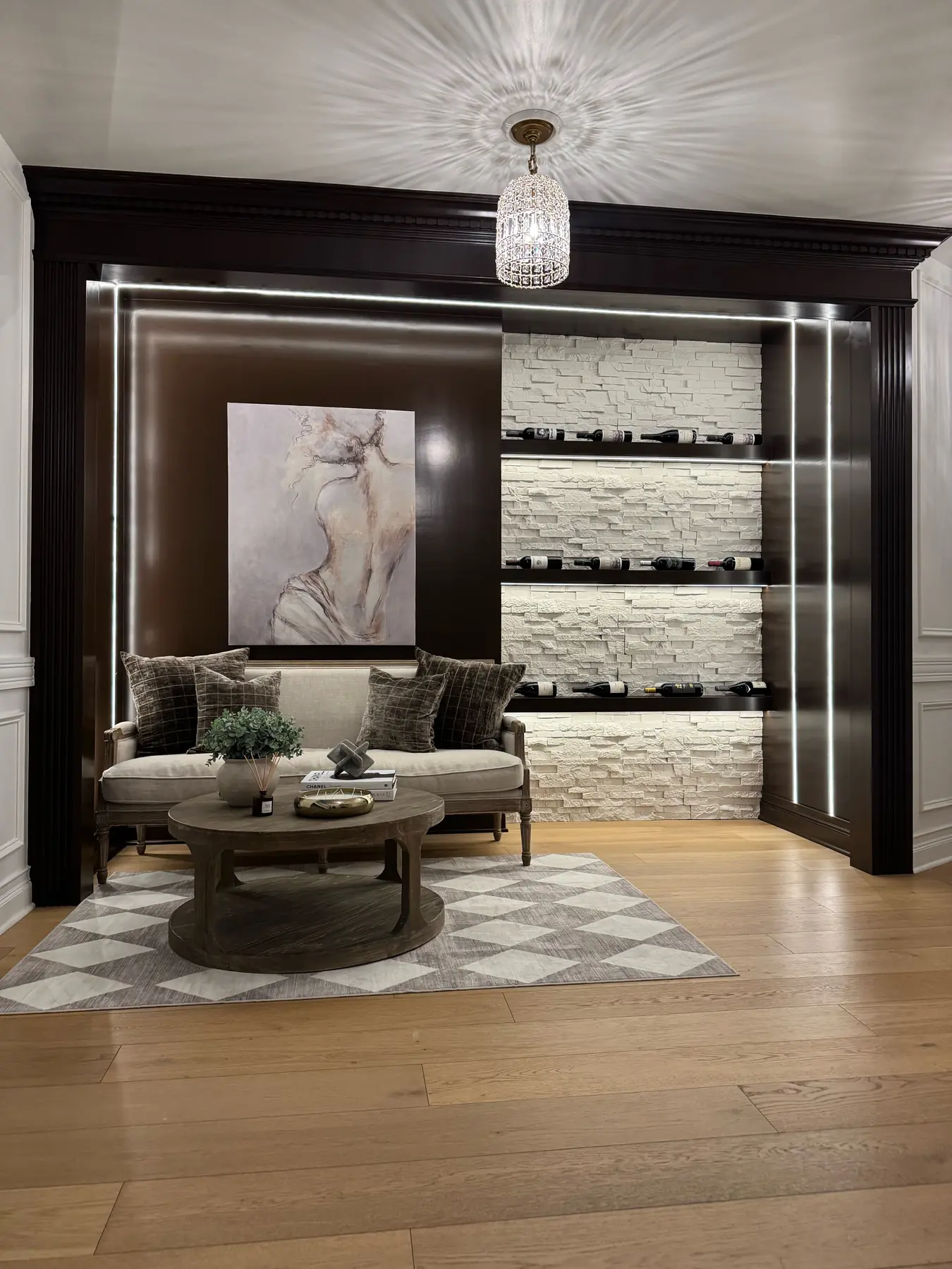 Wine lounge nook with a white stacked-stone wine wall, crystal pendant and settee