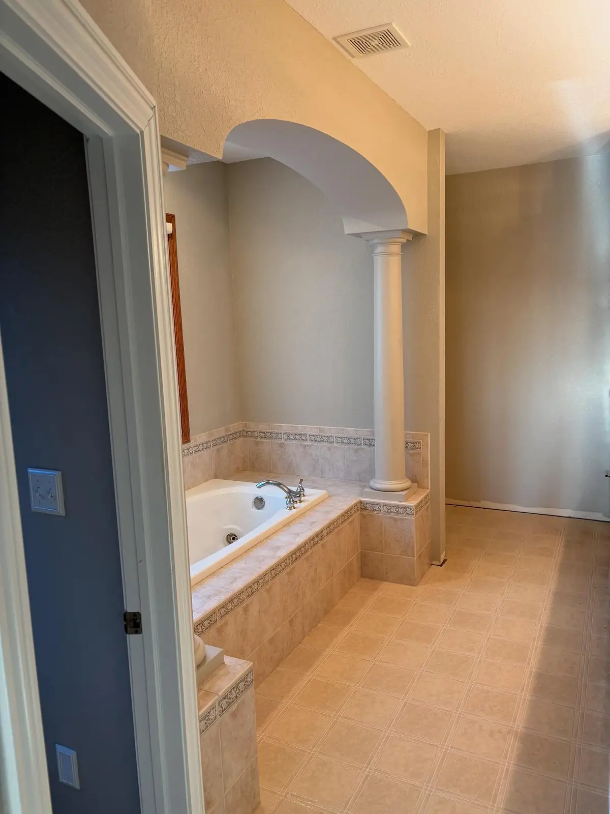 Primary bath before — a tiled tub deck beneath an arch