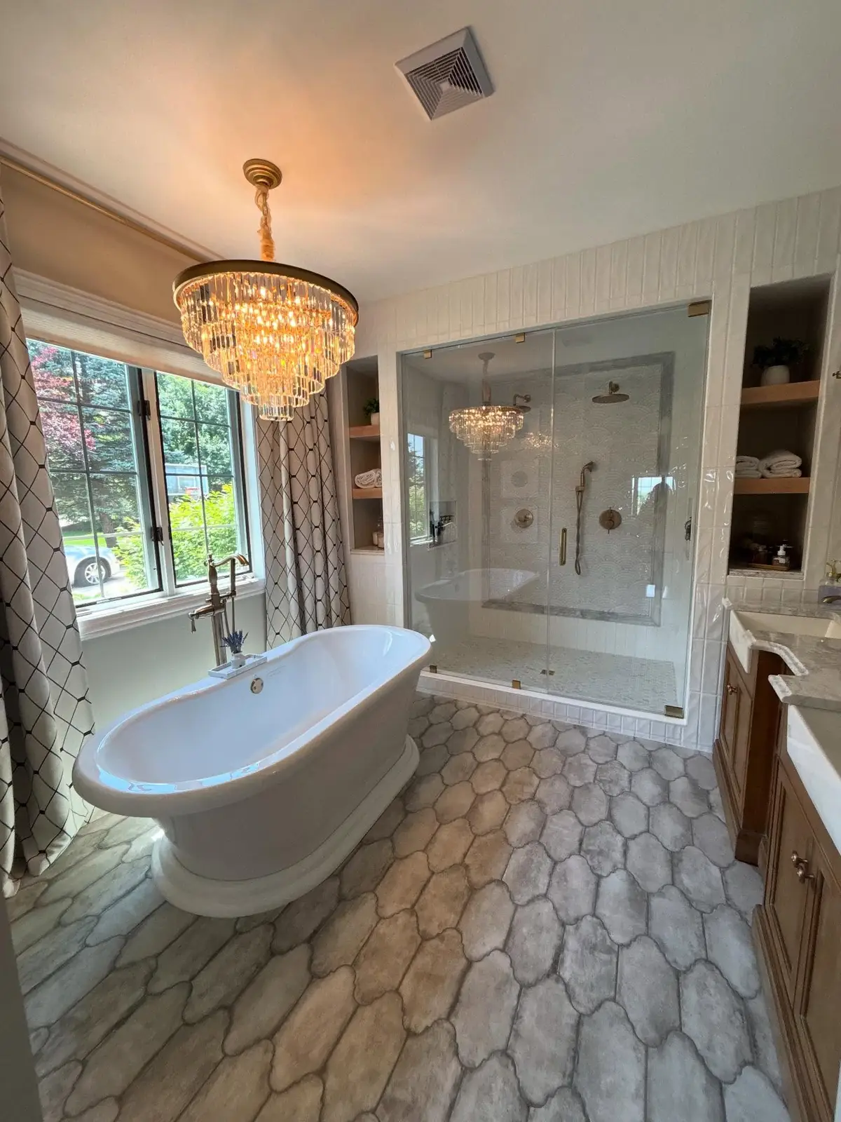 Primary bath after — a freestanding tub beneath a crystal chandelier