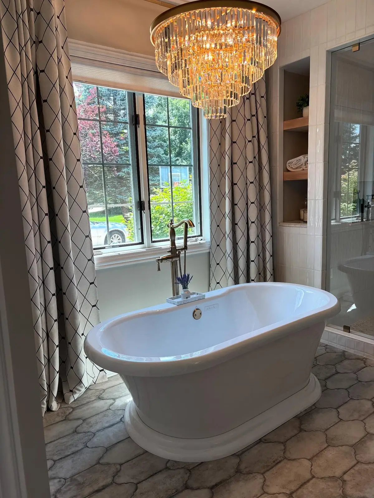 Freestanding tub beneath a crystal chandelier