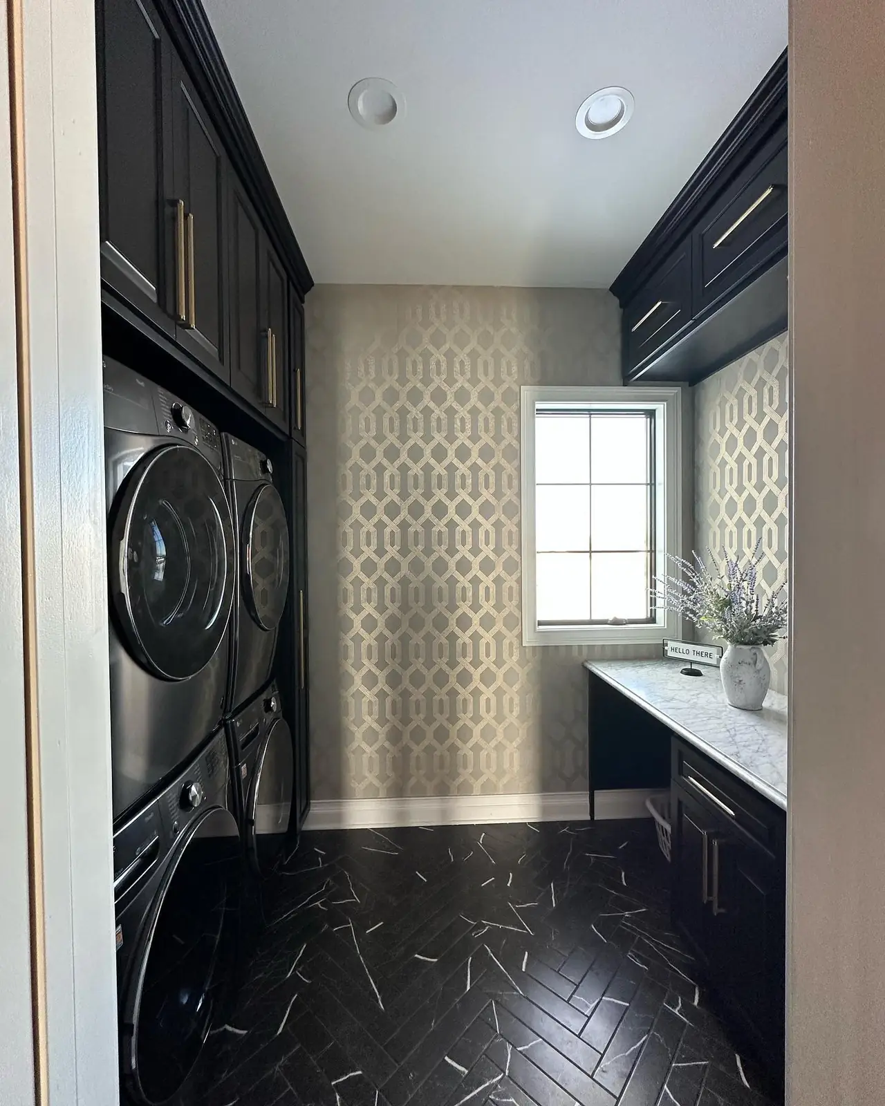 Stacked laundry in dark cabinetry over black herringbone tile — French-Inspired Residence