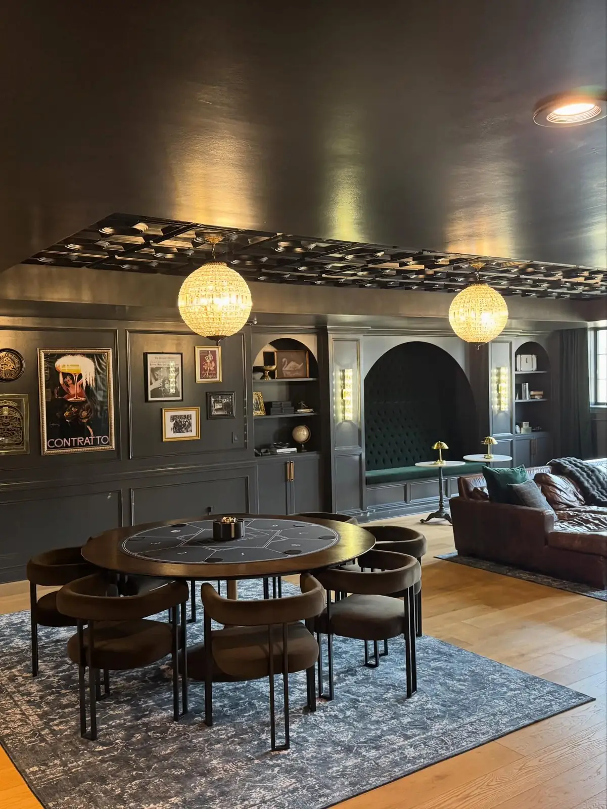 Lounge and game table beneath globe pendants — The Speakeasy Residence
