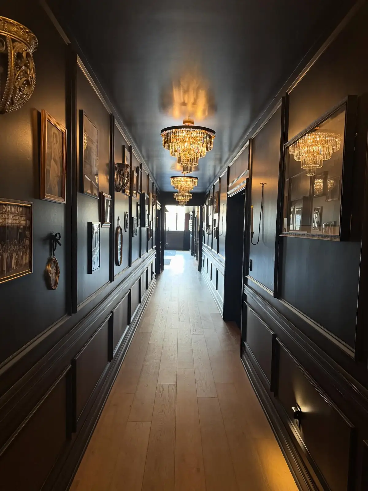 Dark gallery hallway with chandeliers — The Speakeasy Residence