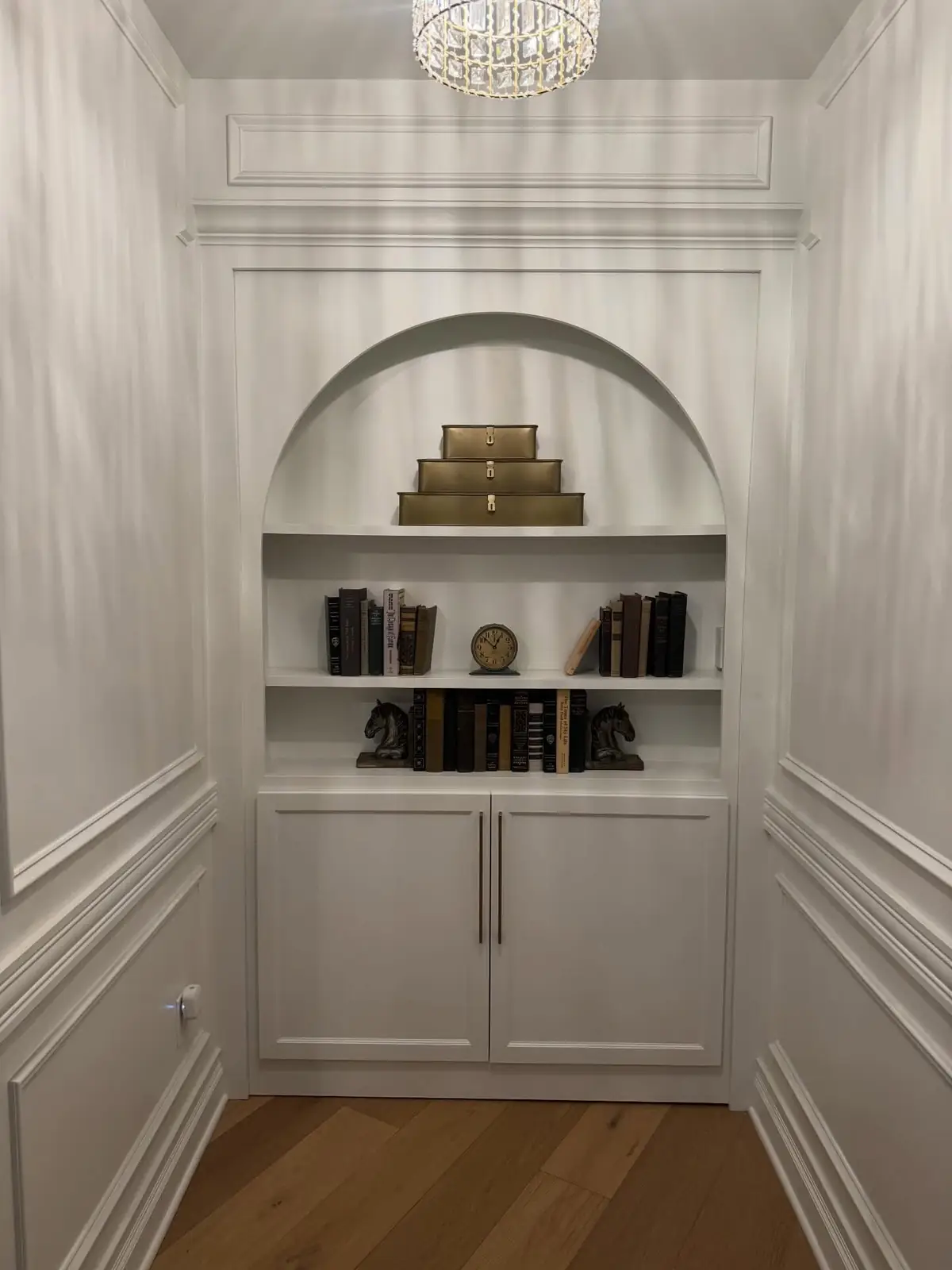 Arched bookcase closed, set into a paneled wall